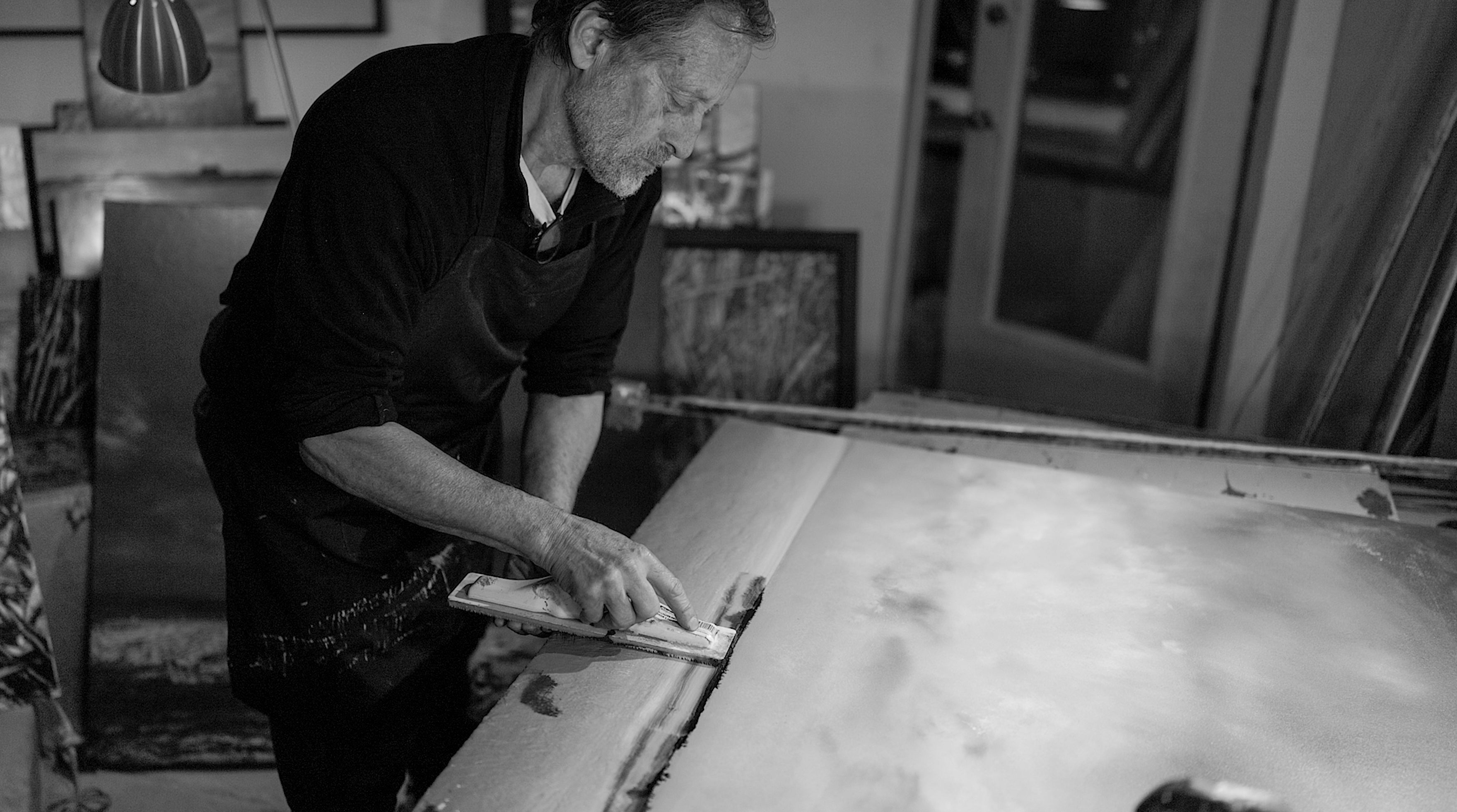 Person working on a large canvas in an art studio