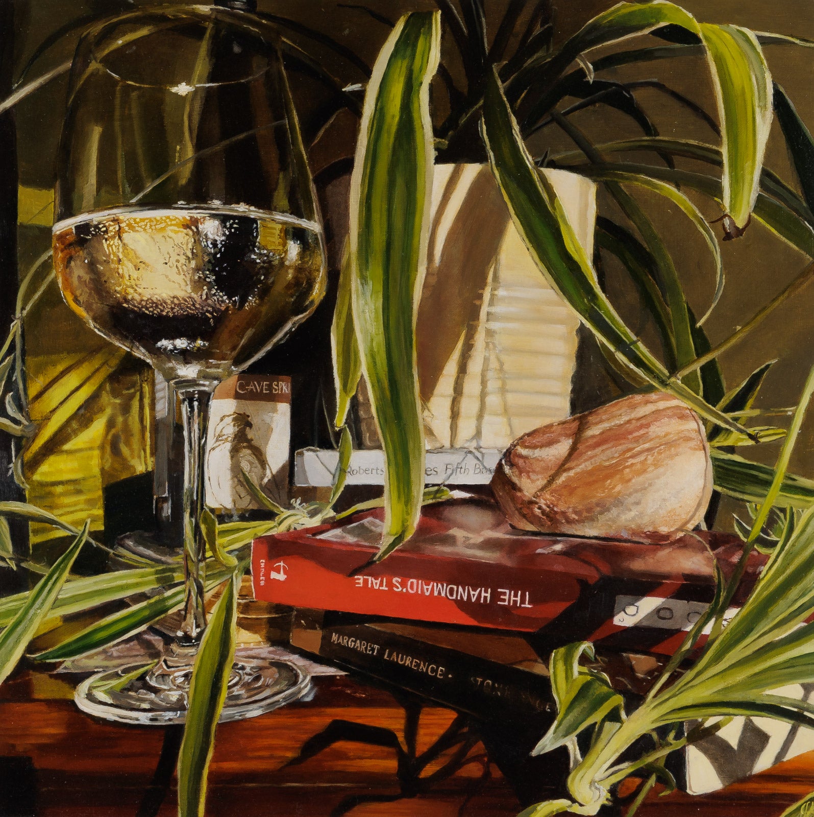 Still life with a glass of wine, books, and a stone on a wooden surface with plants.